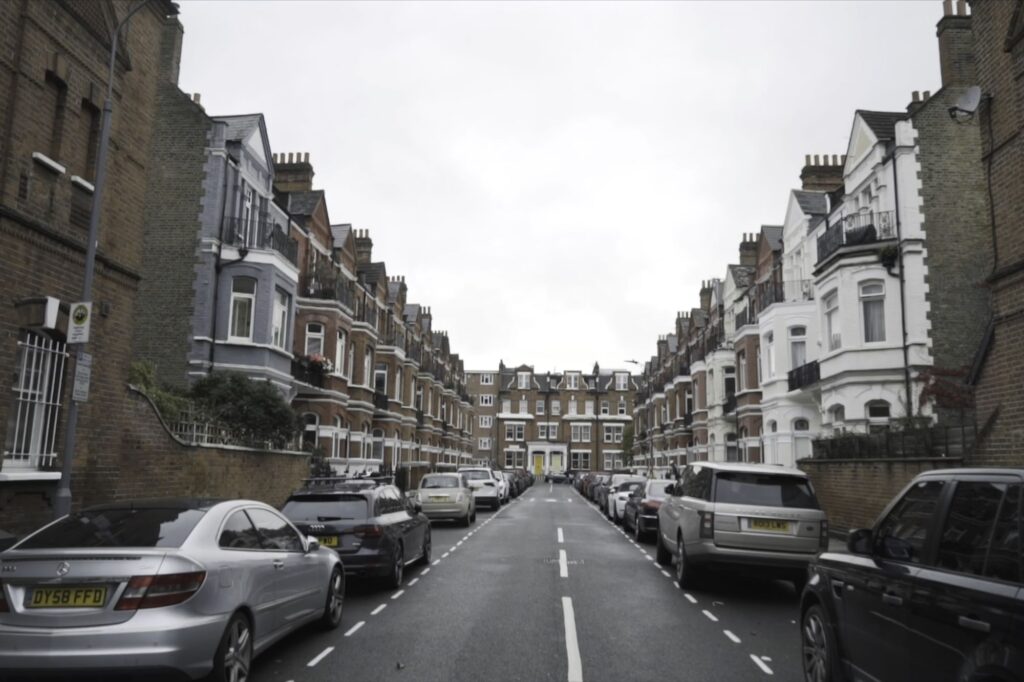 A street of red brick houses and parked cars.