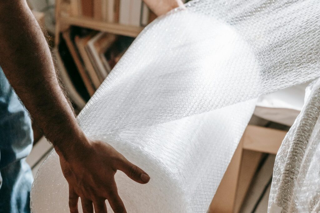 Closeup of a mover's hands holding a roll of bubble wrap in the concept of a good man and van in Walthamstow.