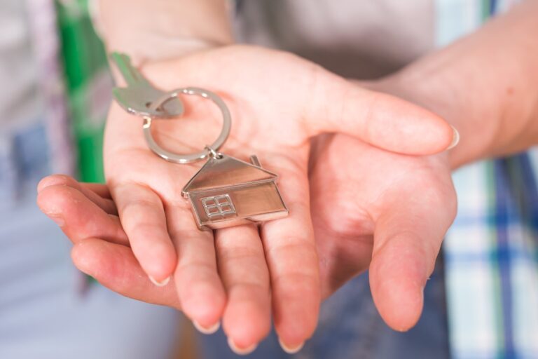 A couple's hands holding a house key with house-shaped keychain in the concept of 'how to save money when moving to Walthamstow.'